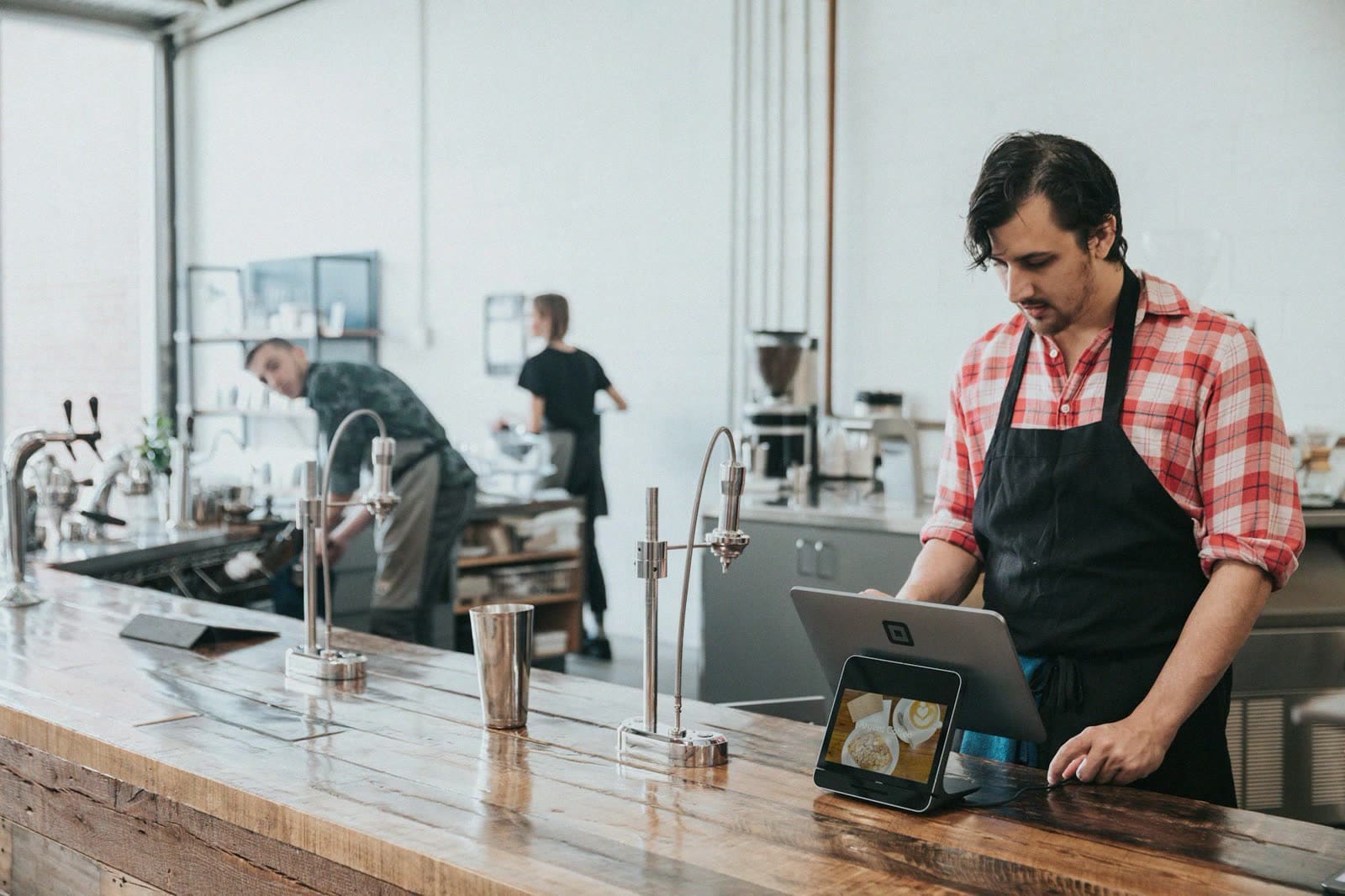 A barista using a tablet at a coffee bar counter