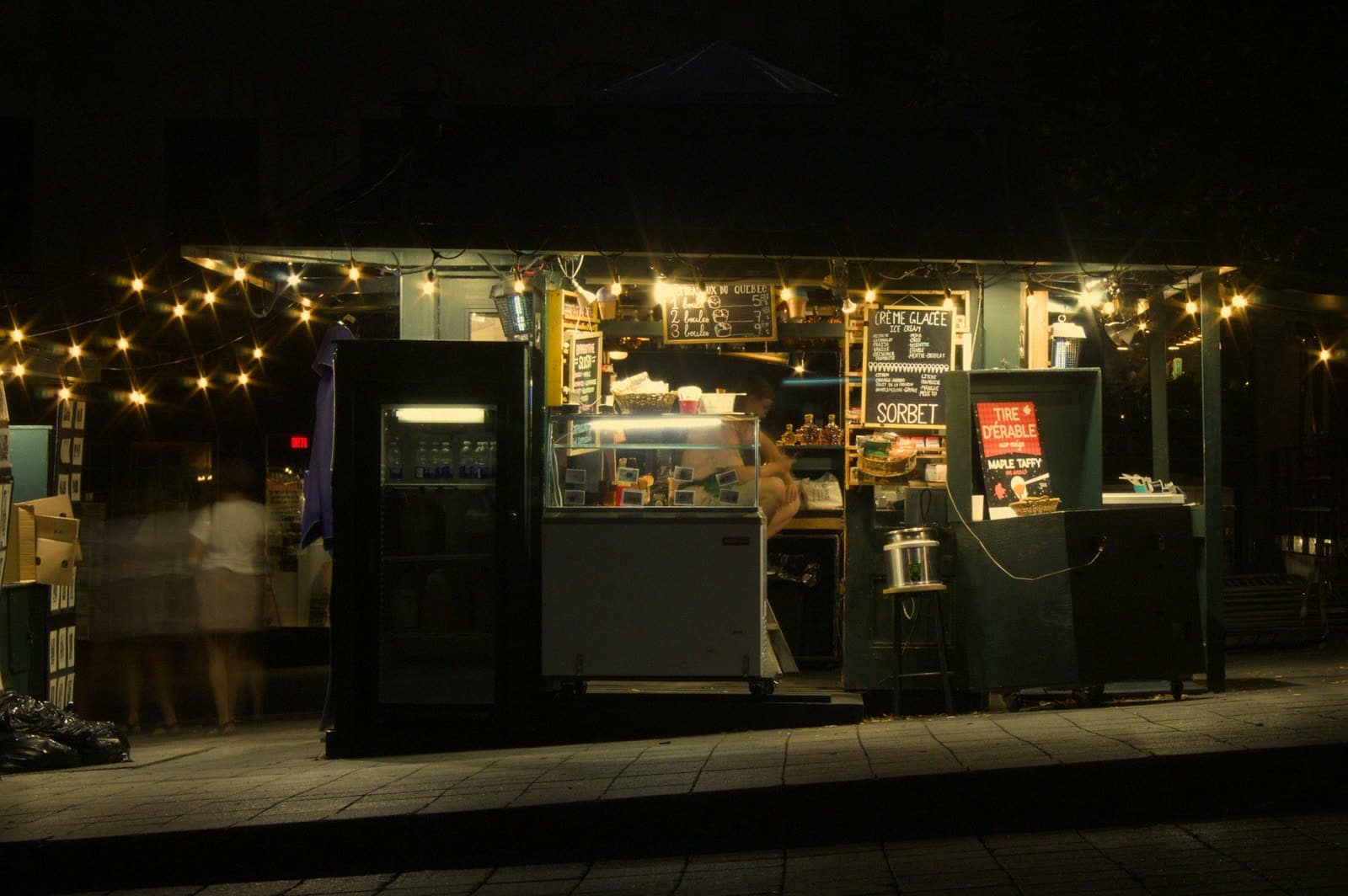 A food stall lit with string lights at night