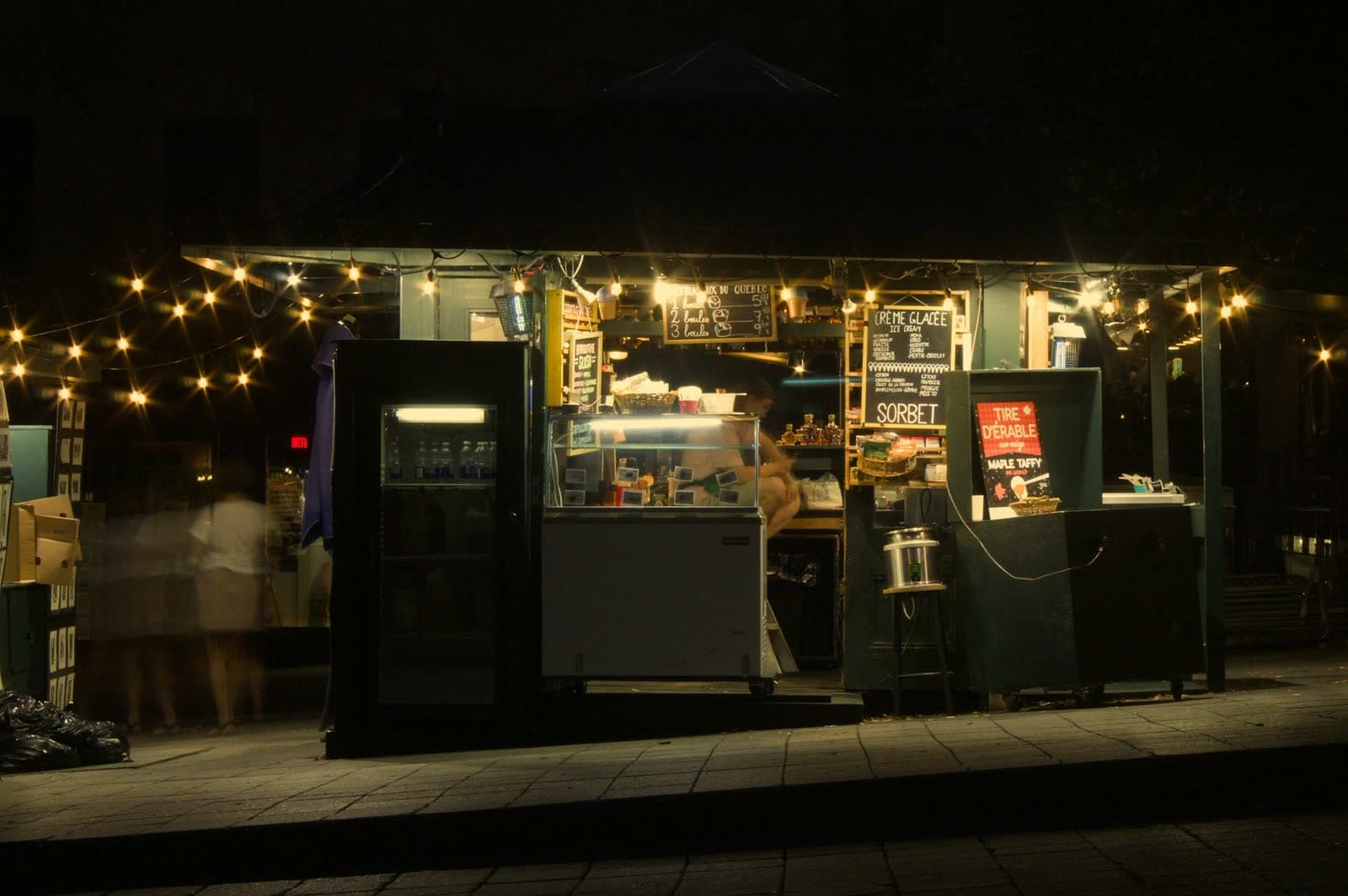 A food stall lit with string lights at night