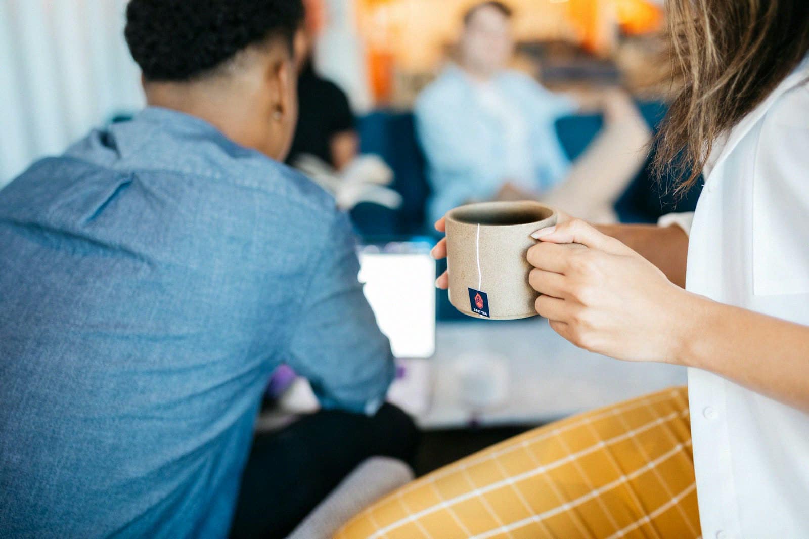 Coworkers at an office table holding coffee mugs