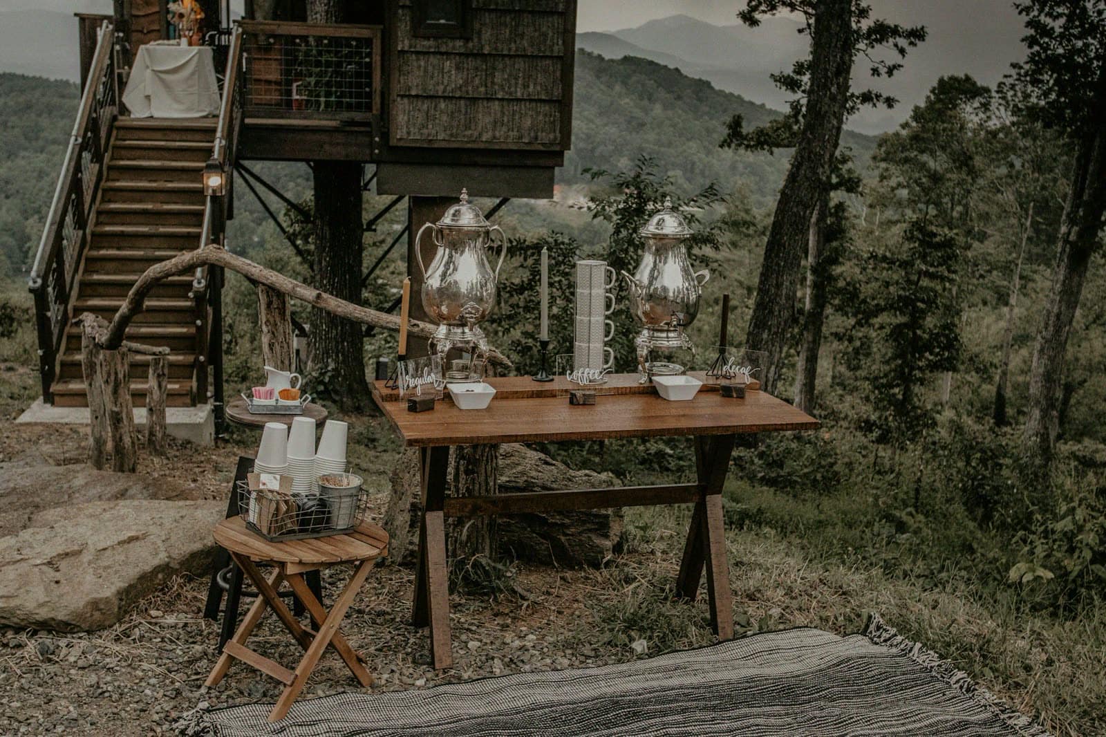 An outdoor coffee station set on a wooden table among trees