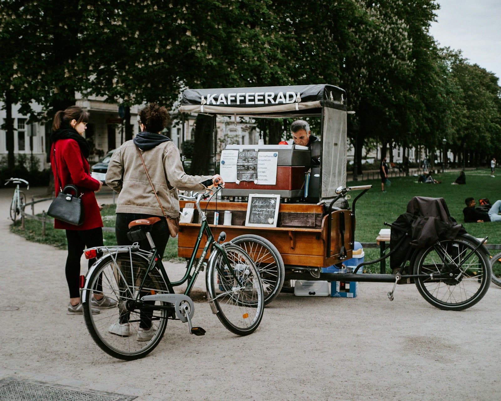Customers with bicycles at a coffee bike cart in a park